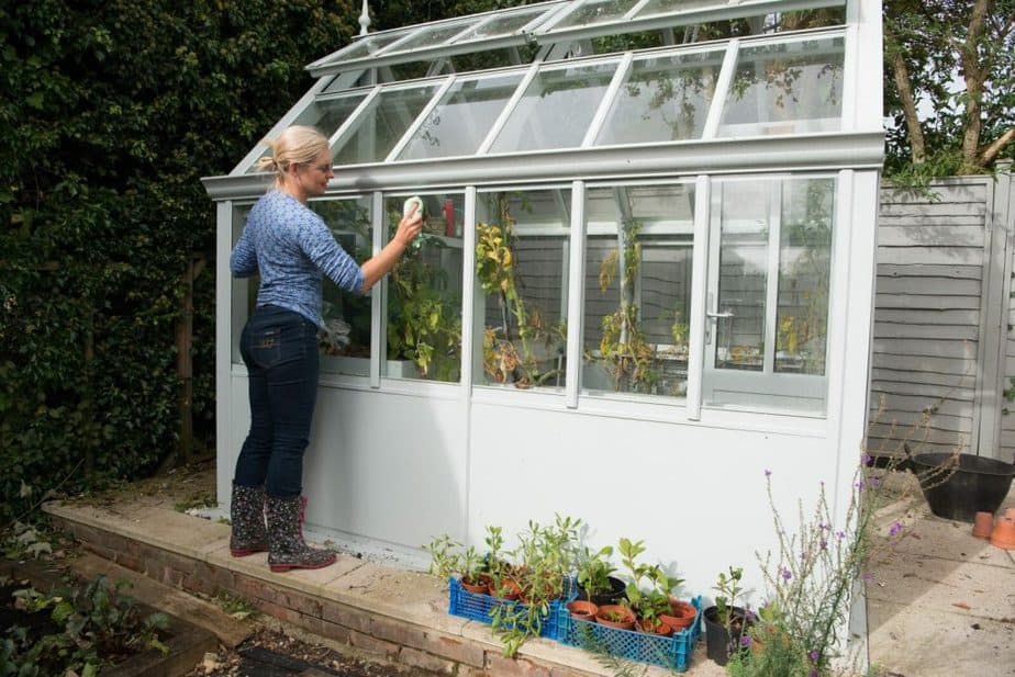 a woman cleaning the glass of a greenhouse